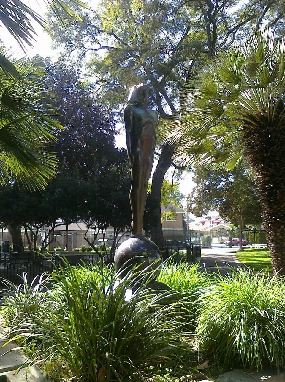 A statue in a park surrounded by trees and plants