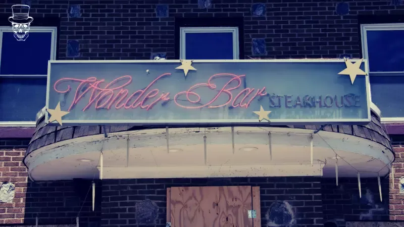 A brick building with a neon sign that says wonder bar steakhouse
