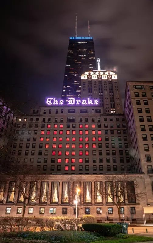 A large building with the word drake on it is lit up at night.