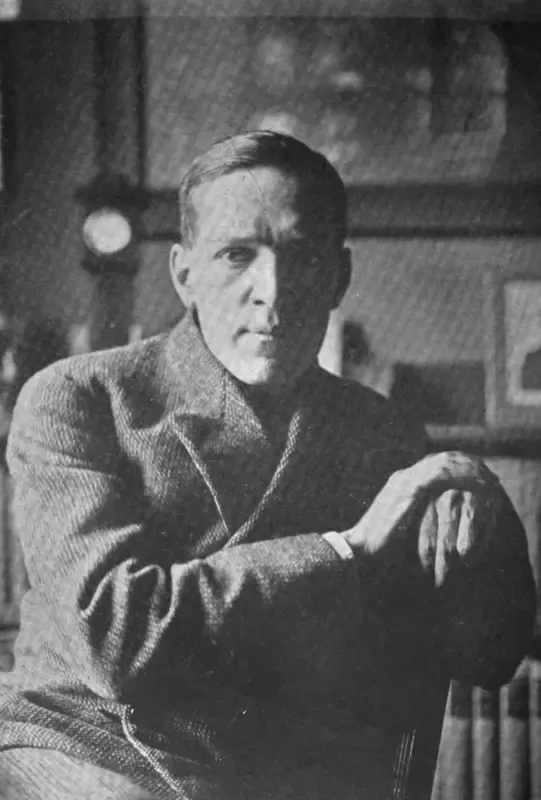 A black and white photo of a man sitting in a chair with his arms crossed.