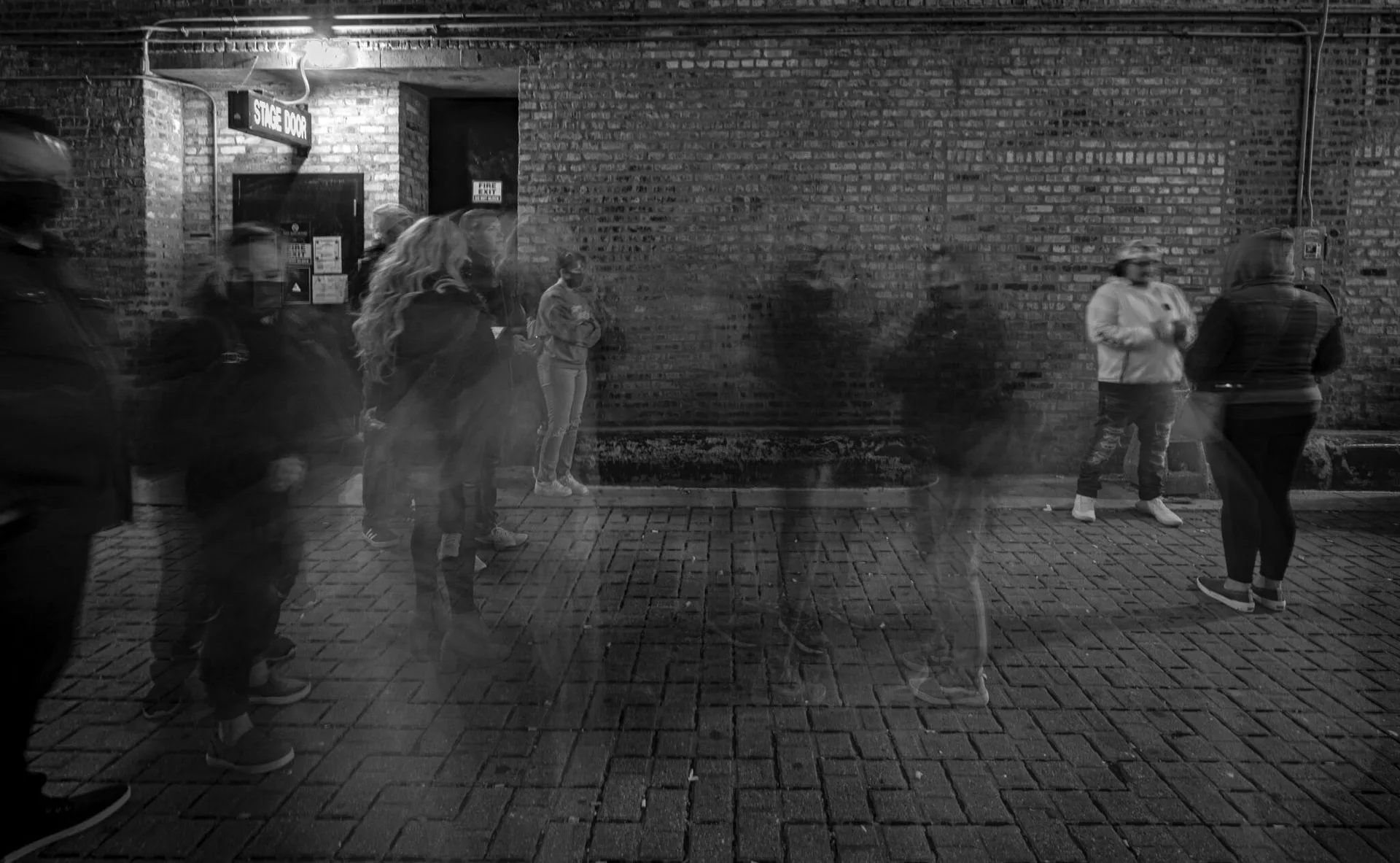 Shadows of people outside of a brick building