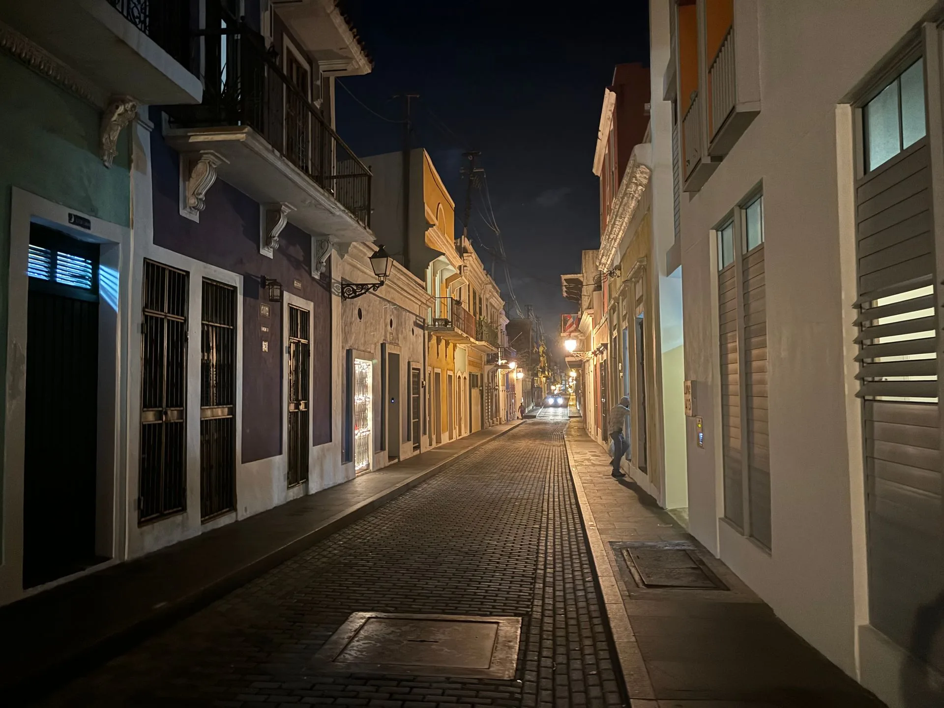 A cobble stone street at night is lined with historic buildings