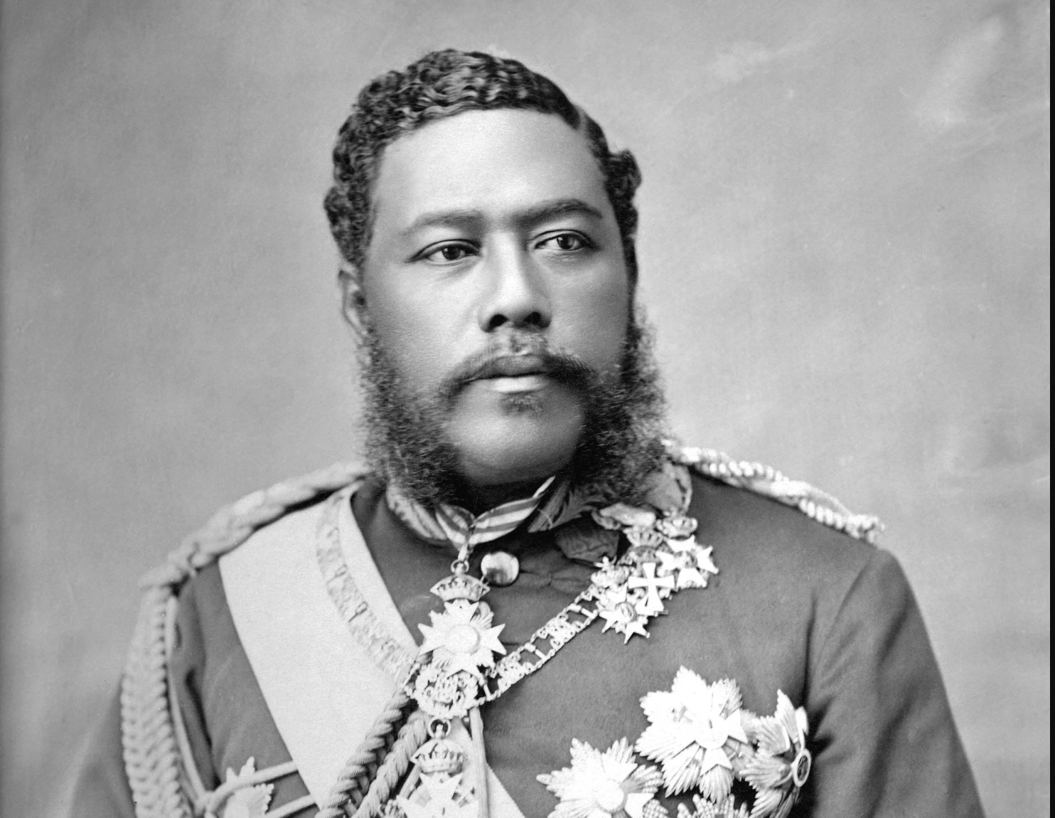 A statue of a man next to a sign that says happy birthday king kalakaua