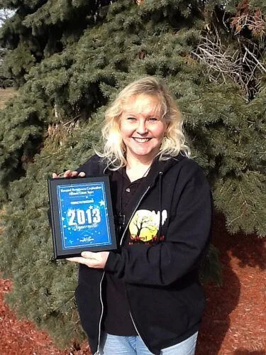 A woman is holding a plaque that says 2013