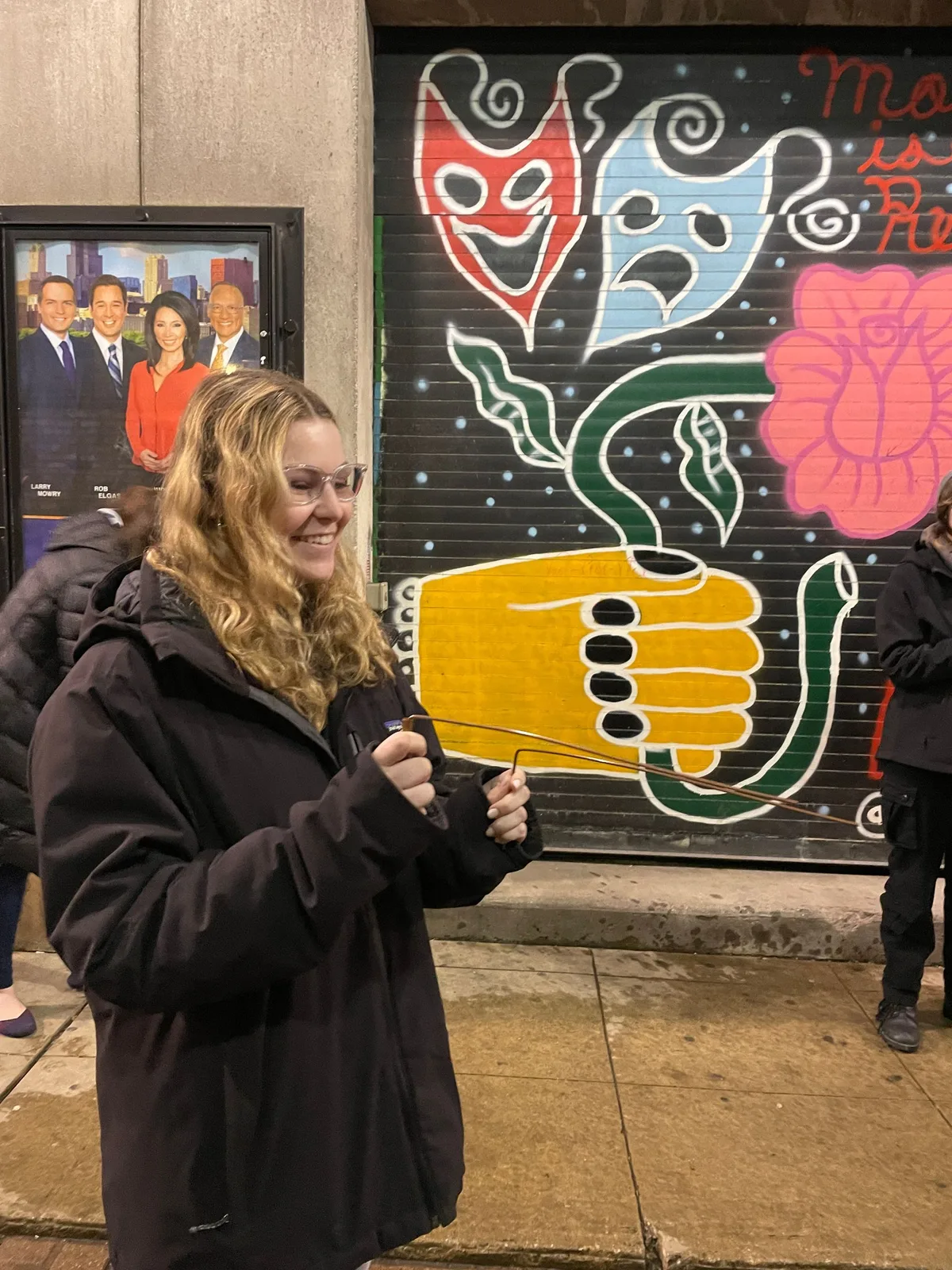 A woman is standing in front of a wall with a painting of a hand holding a snake