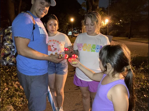 A man in a blue shirt is giving a girl a candle