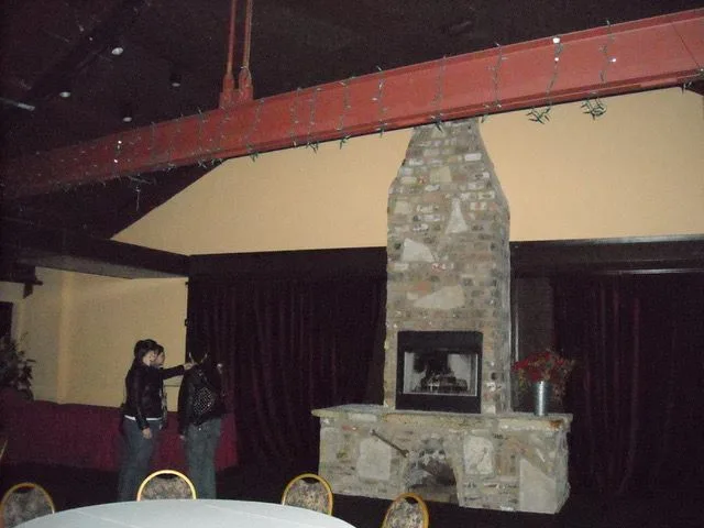 Two people standing in front of a fireplace in a dark room