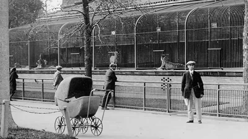 A black and white photo of a baby stroller in front of a zoo